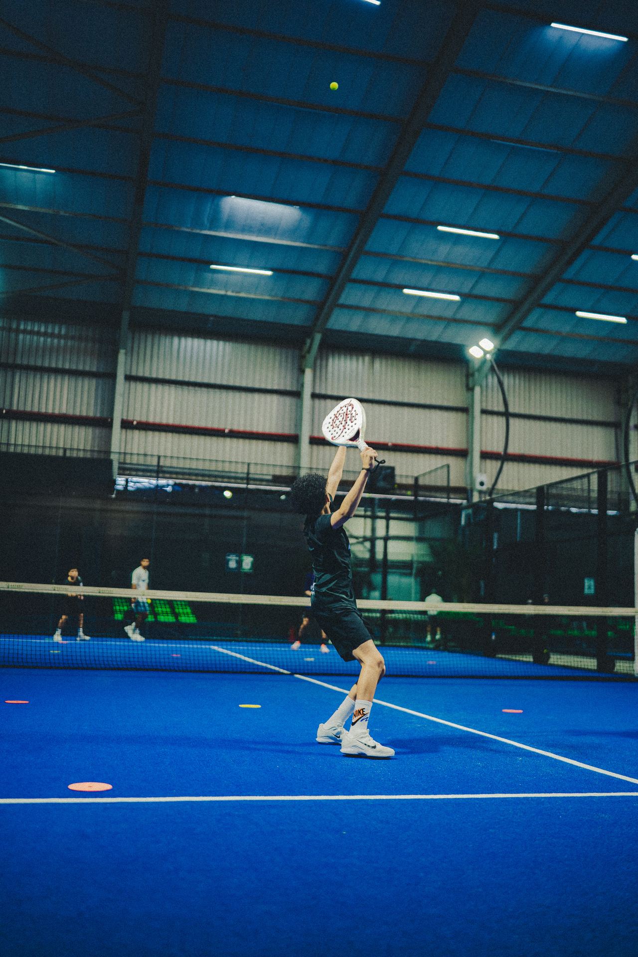Overhead smash during a Blueprint Padel session